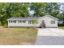 Charming single-story home with light green siding, dark trim, a gray roof, and a mix of gravel and concrete driveway at 5774 Scott White Rd, Hollywood, SC 29449