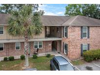 Two-story brick exterior of a building featuring an entryway, balconies, and a well-manicured lawn with a palm tree at 6240 Old Point Rd # C-8, Hanahan, SC 29410
