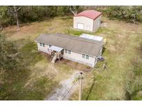 Aerial view of a charming single-story home with a large metal outbuilding in a wooded setting, offering both comfort and functionality at 8476 Old Georgetown Rd, McClellanville, SC 29458