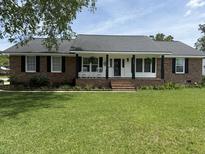 Charming brick home with inviting front porch, rocking chairs, and well-manicured lawn at 1606 Waterside Blvd, Moncks Corner, SC 29461