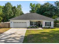 Charming single-story home featuring a well-manicured lawn, neutral siding, black shutters, and a spacious two-car garage at 204 Read St, Moncks Corner, SC 29461
