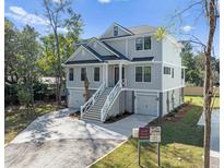 Stunning coastal home with elevated living, showcasing a two-car garage and inviting stairway at 6518 Beagle Club Rd, Meggett, SC 29449