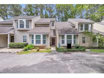 Inviting townhome with beige siding, bay windows, and well-maintained landscaping in a wooded community at 8 Town Park Ln # C, Charleston, SC 29412