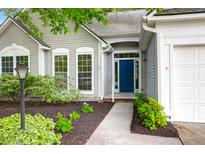 Charming home featuring a light gray exterior, a blue front door, and meticulously landscaped front yard at 8451 Walsham St, North Charleston, SC 29420