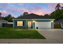 Charming single-story home with teal siding, a well-maintained lawn, and a two-car garage at 8703 Jenny Lind St, North Charleston, SC 29406