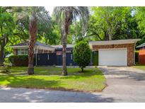 Charming single-story brick home featuring a well-manicured lawn, two palm trees, and an attached garage at 1251 Charlestowne Dr, Charleston, SC 29407
