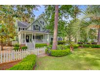 Charming two-story home with a welcoming front porch, lush landscaping, and a white picket fence at 2076 Rookery Ln, Charleston, SC 29414