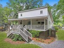Charming two-story home with a large porch, wooden stairs, and mature landscaping at 263 Gator Walk, Ridgeville, SC 29472