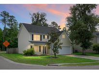 Charming two-story home featuring manicured lawn, attached garage and inviting curb appeal at dusk at 300 Greens Ct, Goose Creek, SC 29445