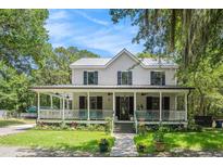 Charming two-story home with a sprawling front porch, lush landscaping, and mature trees at 3002 Edenvale Rd, Johns Island, SC 29455