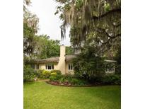 Charming home with manicured lawn and lush landscaping under mature trees draped with Spanish moss at 34 Formosa Dr, Charleston, SC 29407