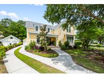 Charming two-story home with yellow siding, lush landscaping, and a curved driveway at 3413 Acorn Drop Ln, Johns Island, SC 29455