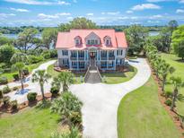 Stunning aerial view of grand home with manicured lawn, circular driveway, and river access at 5625 Crystal Harbor Ln, Hollywood, SC 29449