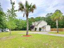 Inviting two-story home featuring a gravel driveway, lush lawn, and mature palm trees at 9489 Sidneys Rd, Round O, SC 29474