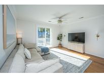 Bright living room featuring hardwood floors, white walls, balcony access, and cozy, neutral-toned sectional sofa at 130 River Landing Dr # 7106, Charleston, SC 29492
