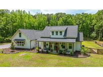 Charming white farmhouse-style home with a welcoming front porch and lush green lawn at 1375 Tannanger Trl, Awendaw, SC 29429