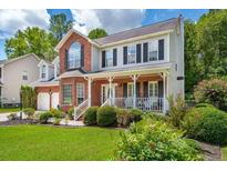 Charming two-story home boasts a brick facade, inviting front porch, and lush landscaping at 143 Belleplaine Dr, Goose Creek, SC 29445