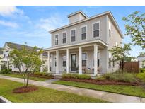Charming two-story home with a large front porch, white columns, and well-manicured landscaping at 716 Triangle Ln, Summerville, SC 29486