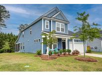 Charming two-story blue home featuring a landscaped yard, attached garage, and welcoming front porch seating at 802 S Pointe Blvd, Summerville, SC 29483