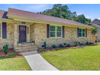 Inviting brick home with manicured lawn, dark shutters, and a charming front entrance with lovely landscape at 924 Trent St, Charleston, SC 29414