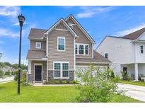Charming two-story home featuring neutral siding, stone accents, and an attached two-car garage at 9998 Winged Elm St, Ladson, SC 29456
