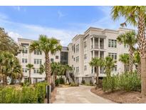 Lowcountry-style condo building with manicured landscaping, mature palms, and covered parking at 108 Fairbanks Oak Aly # 302, Daniel Island, SC 29492