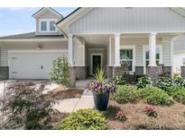 Charming home featuring a landscaped front yard, inviting porch, and attached garage at 1273 Locals St, Summerville, SC 29485