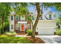 Charming two-story home featuring a brick facade, siding, a welcoming orange front door, and lush landscaping at 174 Revetment Ln, Mount Pleasant, SC 29464