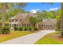 Stately brick home with a well-manicured lawn and long driveway, surrounded by lush trees under a blue sky at 2221 Black Oak Ct, Mount Pleasant, SC 29466