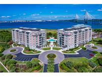 Stunning aerial view of luxury condos with a pool, lush landscaping, and waterfront scenery featuring a majestic bridge at 235 S Plaza Ct Ct # 212, Mount Pleasant, SC 29464