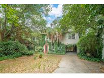 Two story home featuring a red door, mature trees, driveway, and partial under-house parking at 3109 Ion Ave, Sullivans Island, SC 29482