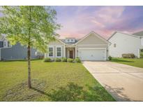 Charming single-story home featuring a well-manicured lawn and a two-car garage, complemented by mature landscaping at 311 Beachgrass Ln, Summerville, SC 29486