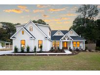 Beautiful two-story home featuring a pristine green lawn and attractive landscaping at sunset at 477 Yellow House Pl, Charleston, SC 29492