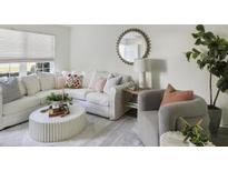 Bright living room with a large sofa, round mirror, plants, and plenty of natural light at 519 Parkdale Dr # J, Charleston, SC 29414