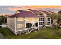 Beautiful condo exterior featuring a red roof, gray siding, and large windows at 63 Mariners Cay, Folly Beach, SC 29439