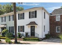 Charming two-story white stucco home with black shutters and a well-manicured front yard at 166 1/2 Queen St, Charleston, SC 29401