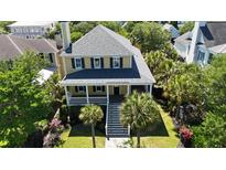 Charming two-story yellow home with lush landscaping and a welcoming front porch at 2449 Daniel Island Dr, Daniel Island, SC 29492