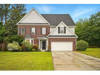 Charming two-story brick home with manicured lawn and attached two-car garage at 317 Sabal Palmetto Ct, Moncks Corner, SC 29461