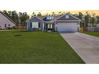 Charming single-story home with a well-manicured lawn, attached garage, and inviting curb appeal at 1144 Wading Point Blvd, Huger, SC 29450