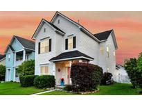 Charming two-story white home with black shutters, lush landscaping, and inviting curb appeal against a colorful evening sky at 221 Trillium Ave, Summerville, SC 29483