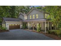 Beautiful two-story home with a covered front porch, two-car garage, and a gravel driveway surrounded by mature trees at 32 Middleton Oaks Rd, Charleston, SC 29414