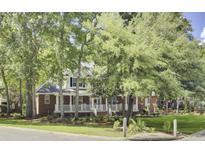 Charming two-story home with red brick and white trim, featuring a welcoming front porch and lush landscaping at 4217 Meadowbrook Ct, North Charleston, SC 29420