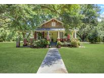 Charming home featuring a well-manicured lawn, inviting porch, and beautiful mature trees at 5126 Highway 174, Hollywood, SC 29449
