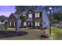 Charming two-story home with brick and siding exterior, complemented by lush landscaping and mature trees at 555 Pointe Of Oaks Rd, Summerville, SC 29485