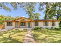 Charming single-story home featuring a white brick exterior, wood accents, and a beautifully landscaped front yard at 841 Fred St, Charleston, SC 29412
