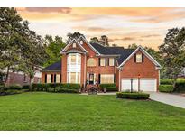 Beautiful two-story brick home with manicured lawn, black shutters, mature trees and two-car garage at 8662 W Fairway Woods Dr, North Charleston, SC 29420