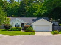 Charming one-story home with manicured lawn, lush landscaping, and attached two-car garage in a suburban neighborhood at 9590 Crosscut Dr, Ladson, SC 29456
