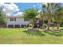Charming home with manicured lawn, mature trees, and inviting front porch with stairs leading to the front door at 1125 Oceanview Rd, Charleston, SC 29412
