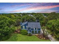 Lovely home with blue siding, mature trees, lush lawn, and well-manicured landscaping at 13 32Nd Ave, Isle of Palms, SC 29451