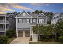 Charming two-story home featuring double garage doors, and a welcoming front entrance with palm trees at 1569 Red Tide Rd, Mount Pleasant, SC 29466